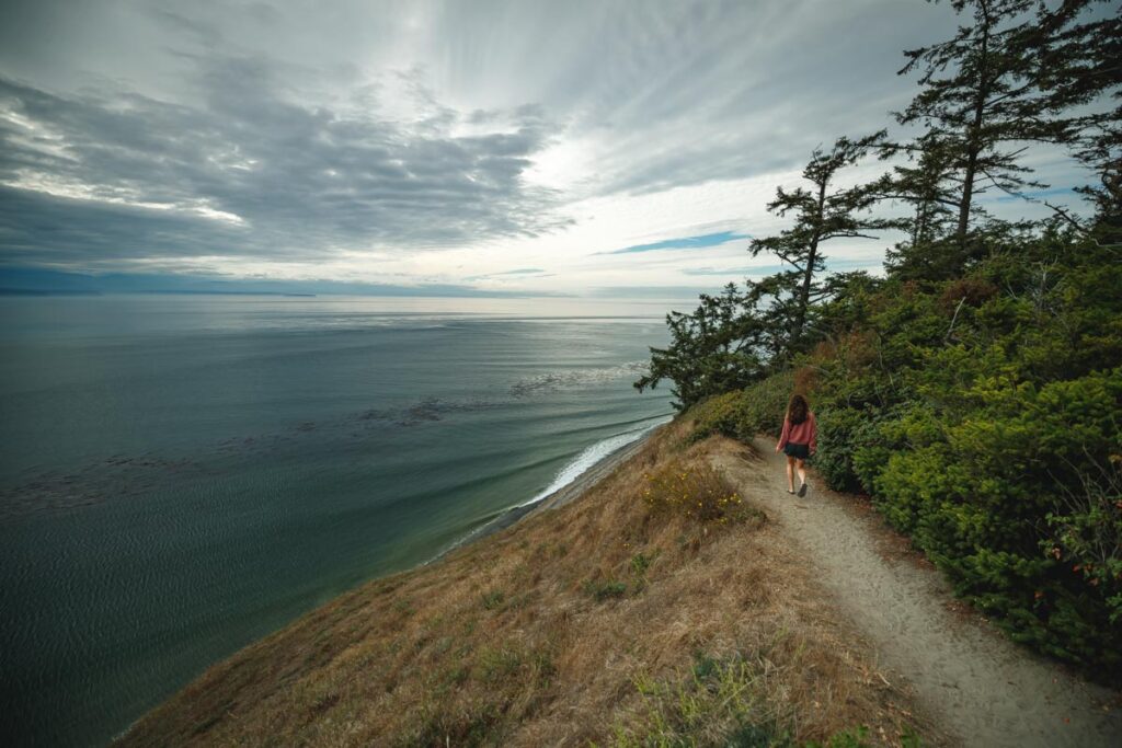 Woman walking on clifftop trail in Fort Ebey State Park, Washington