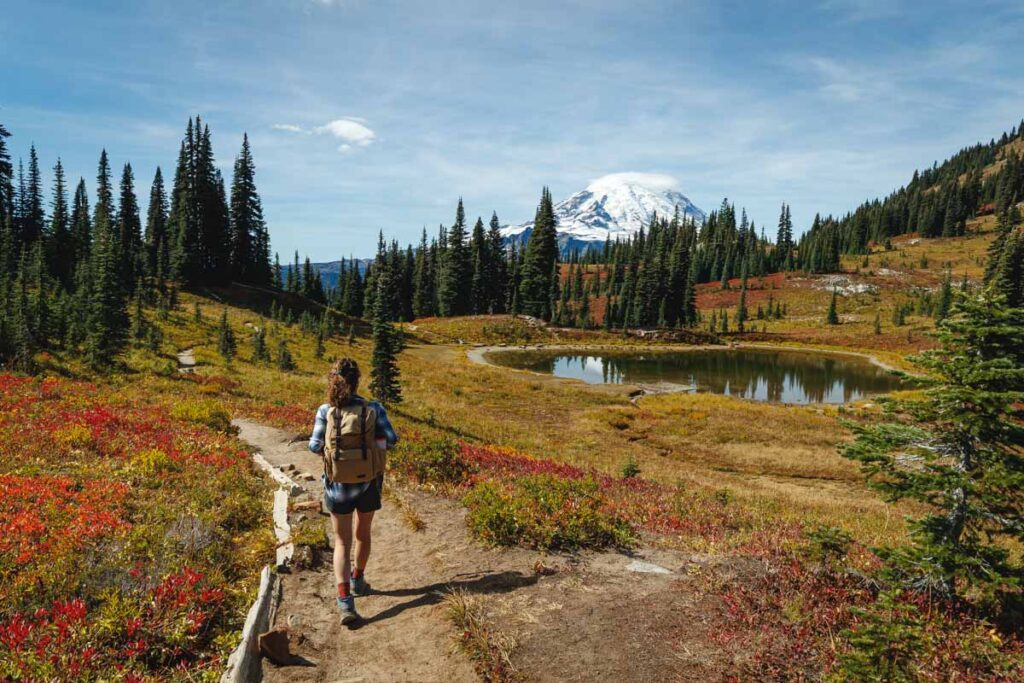 Woman hiking past a small lake on the Naches Peak Loop Trail in Washington.