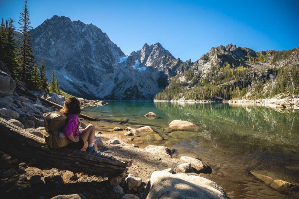 Woman sitting at Colchuck Lake, Washington for the best weekend getaways from Seattle