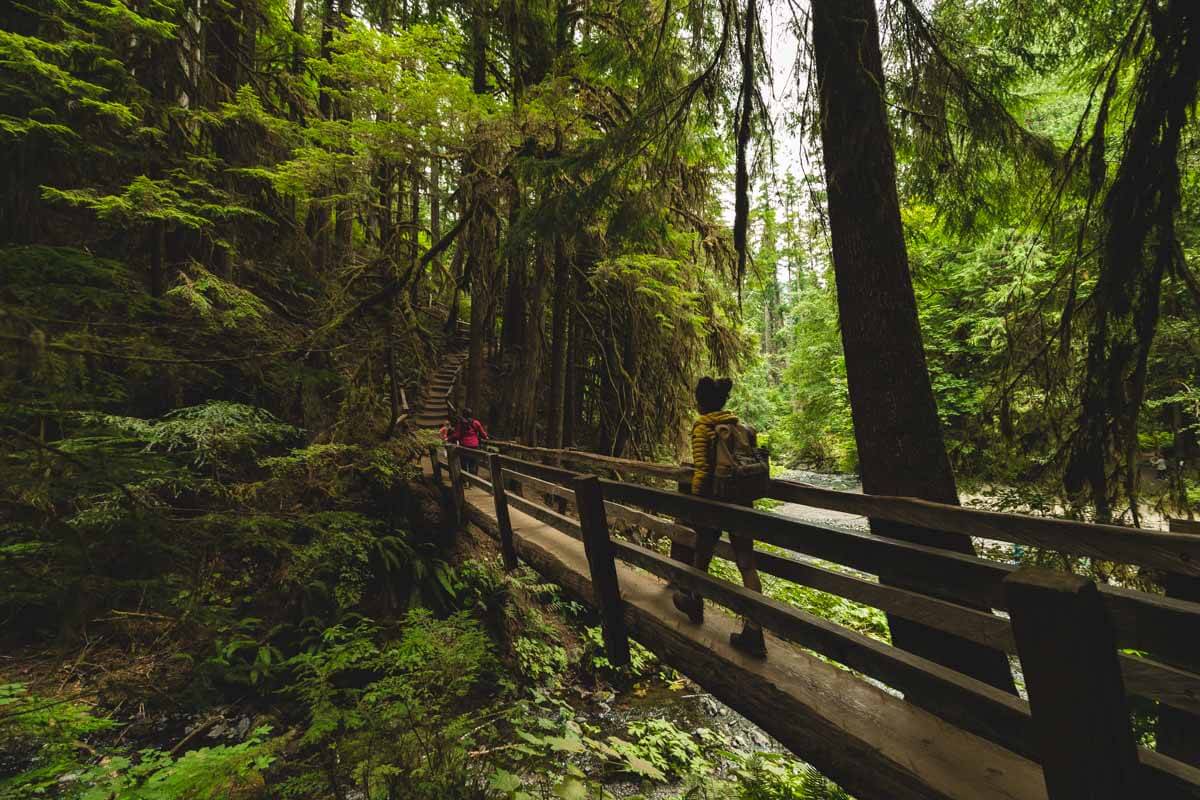 Woman crossing wooden bridge on the trail to Marymere Falls.