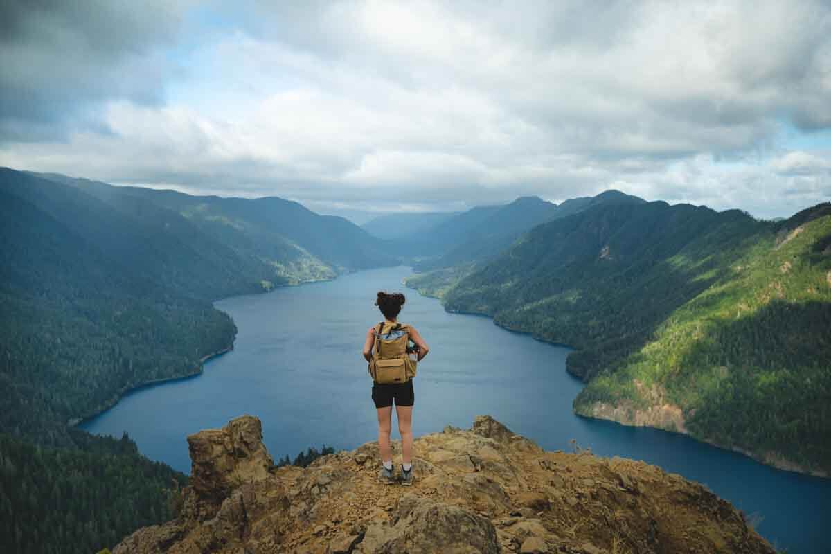 Woman on the summit of Mount Storm King with Lake Crescent and mountains in back.