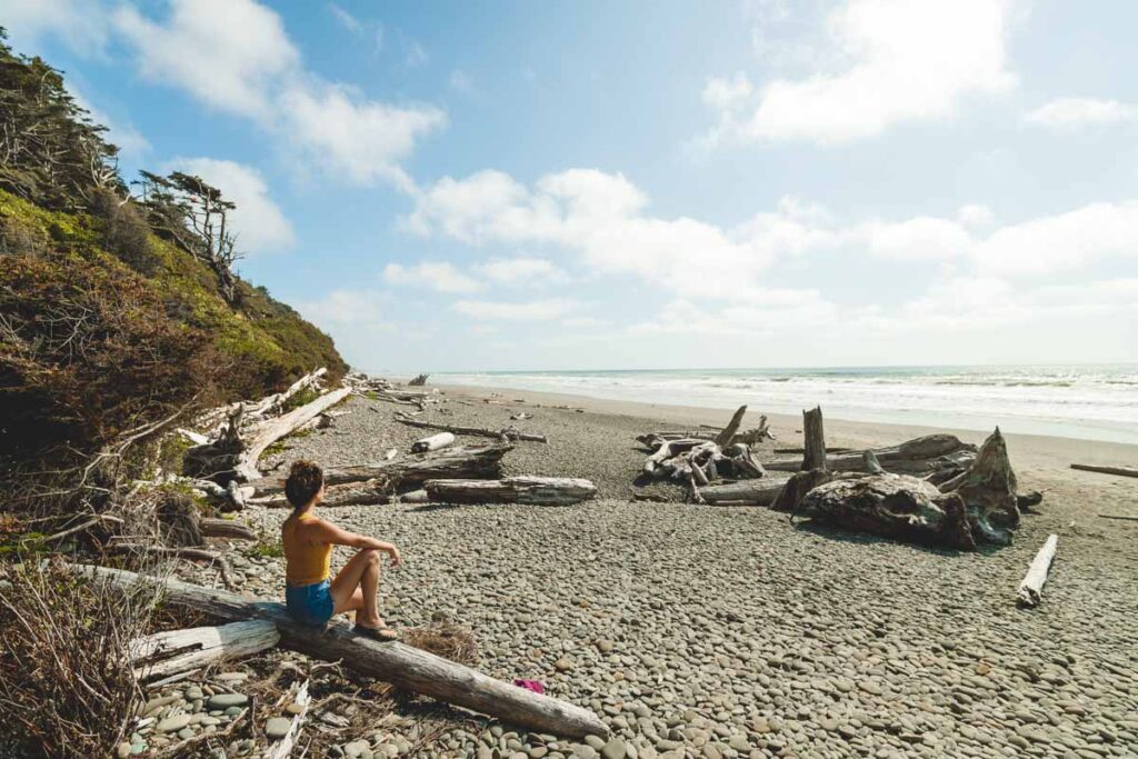 Woman on driftwood on Second Beach near La Push, where to stay in Olympic National Park