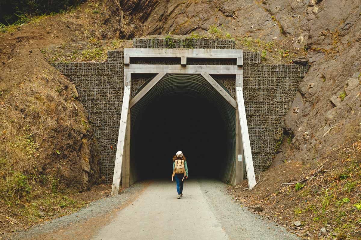 Nina entering a tunnel that heads into a cliff along the Spruce Railroad Trail.