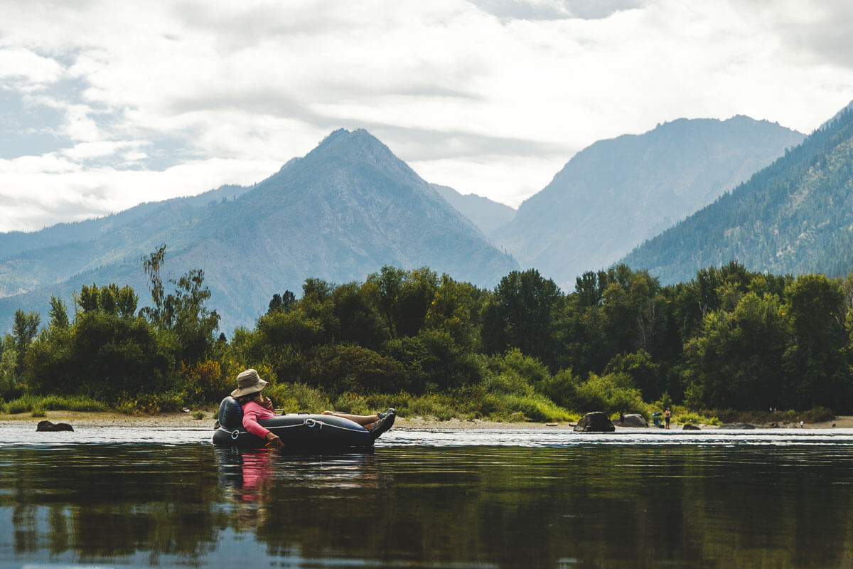 Person tubing on along Wenatchee River with mountain views near Leavenworth.
