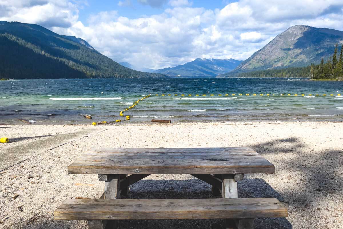 Empty picnic bench besides Lake Wanatchee with views of distant hills.