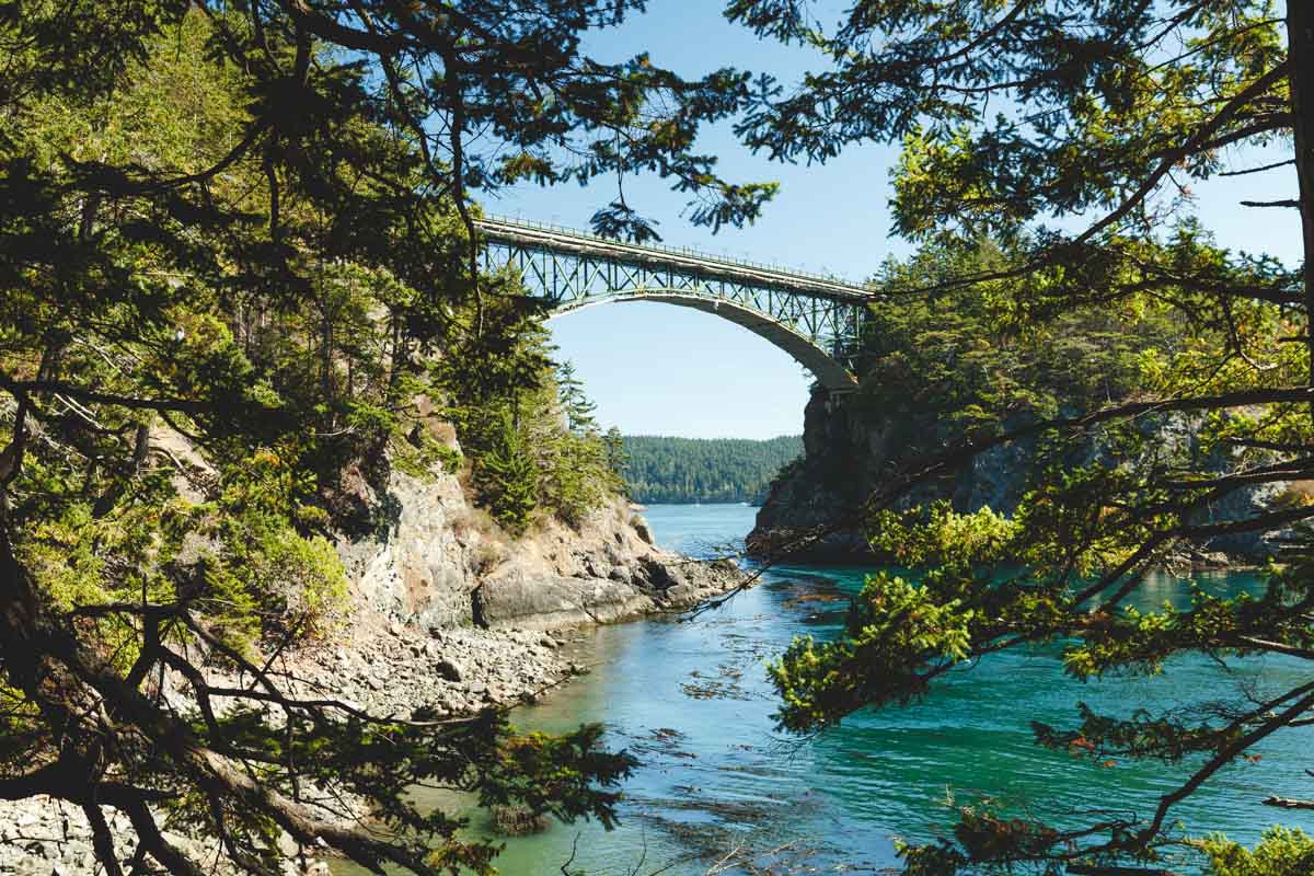 A view of a suspension bridge connecting two land masses from Lottie Trail in Deception Pass State Park.