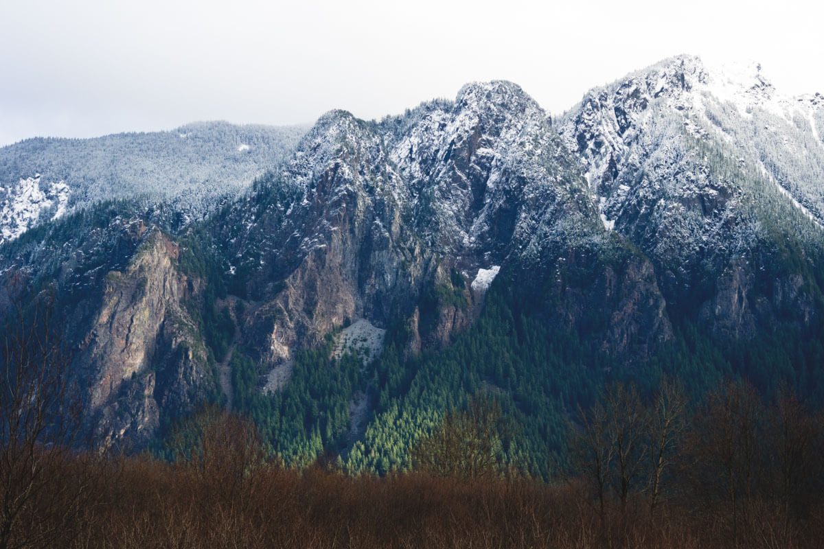 The large peak of Mount Si covered in a dusting of snow on an overcast day.