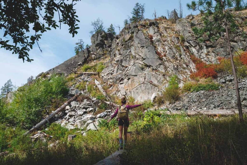 A woman balancing on a fallen tree in front of the Painted Rocks along the nature trail.