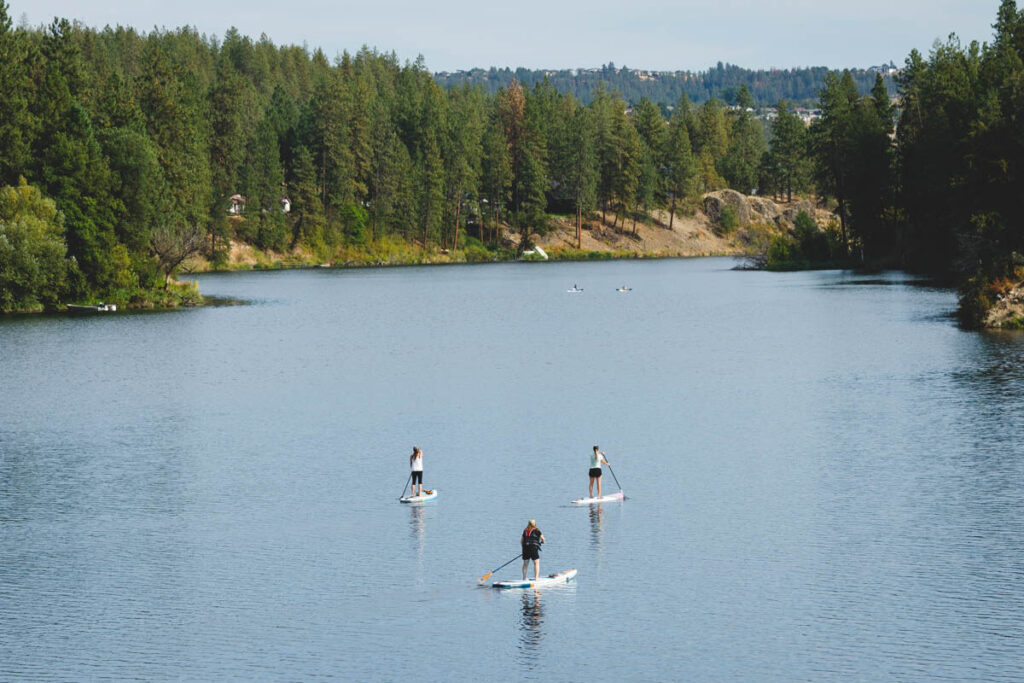 Three women paddle boarding on Lake Spokane in Riverside State Park.