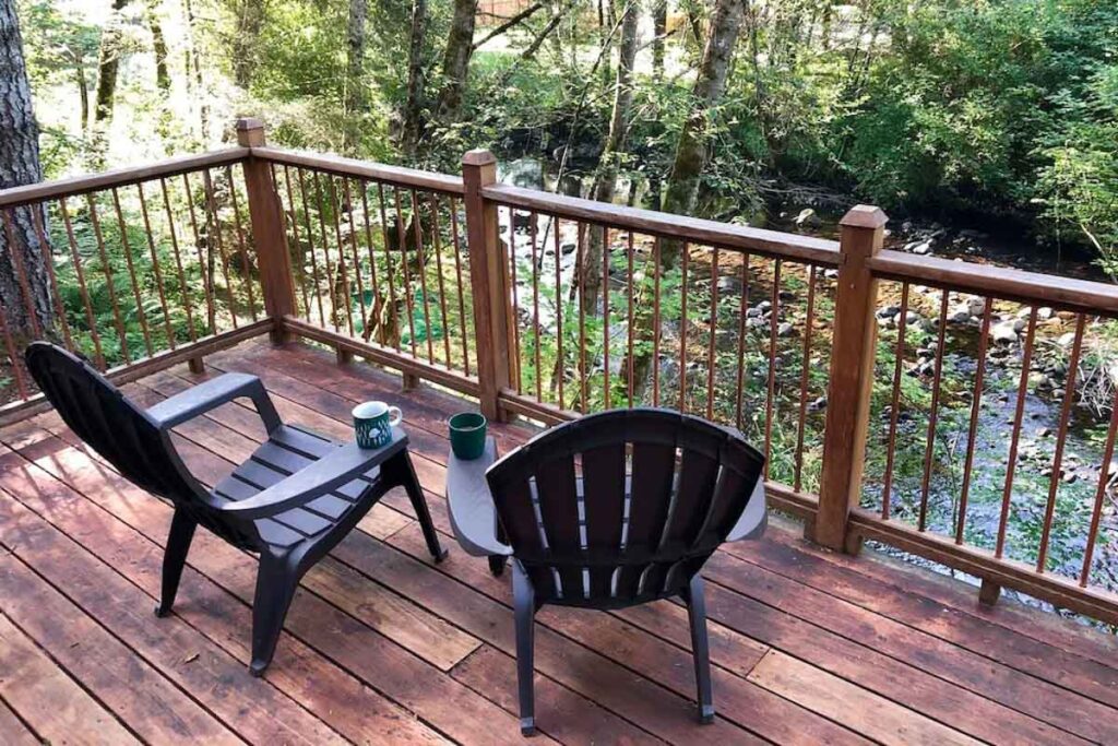 Two deck chairs on the balcony of a creek-front cabin near Mount Rainier in Washington.