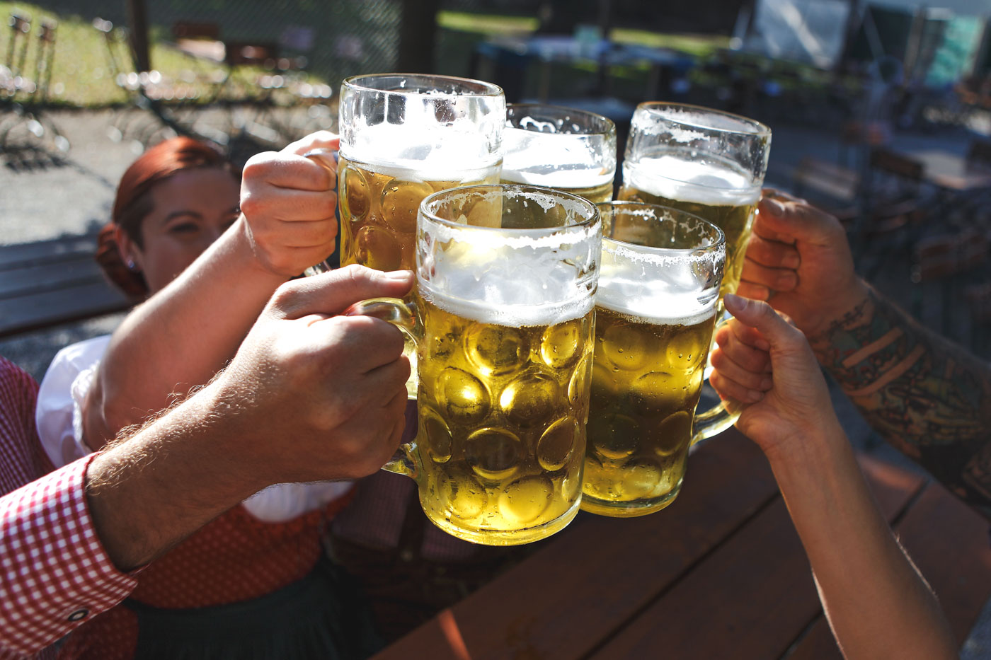 A group of people cheers-ing steins of beer.