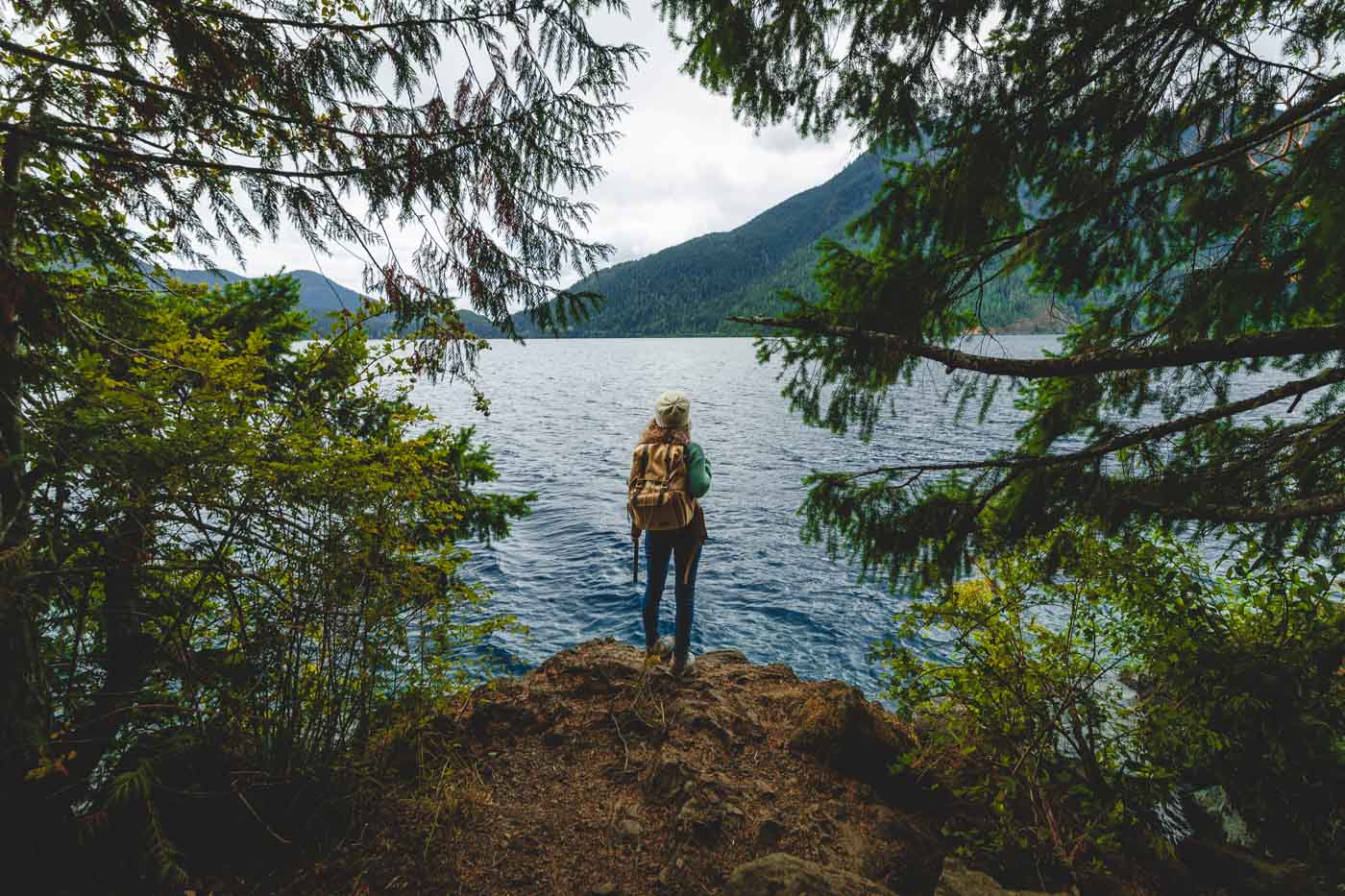 Nina standing on the edge of the Spruce Railroad Trail on the shores of the Devil's Punchbowl frame by trees.