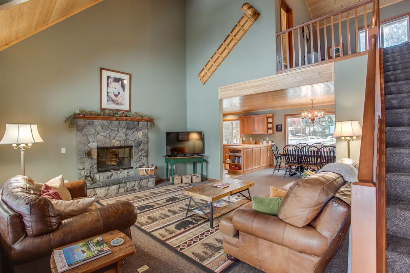 Leather sofas in the cost living room area of Serene Mountain View Cabin with a view to the dining area and kitchen.