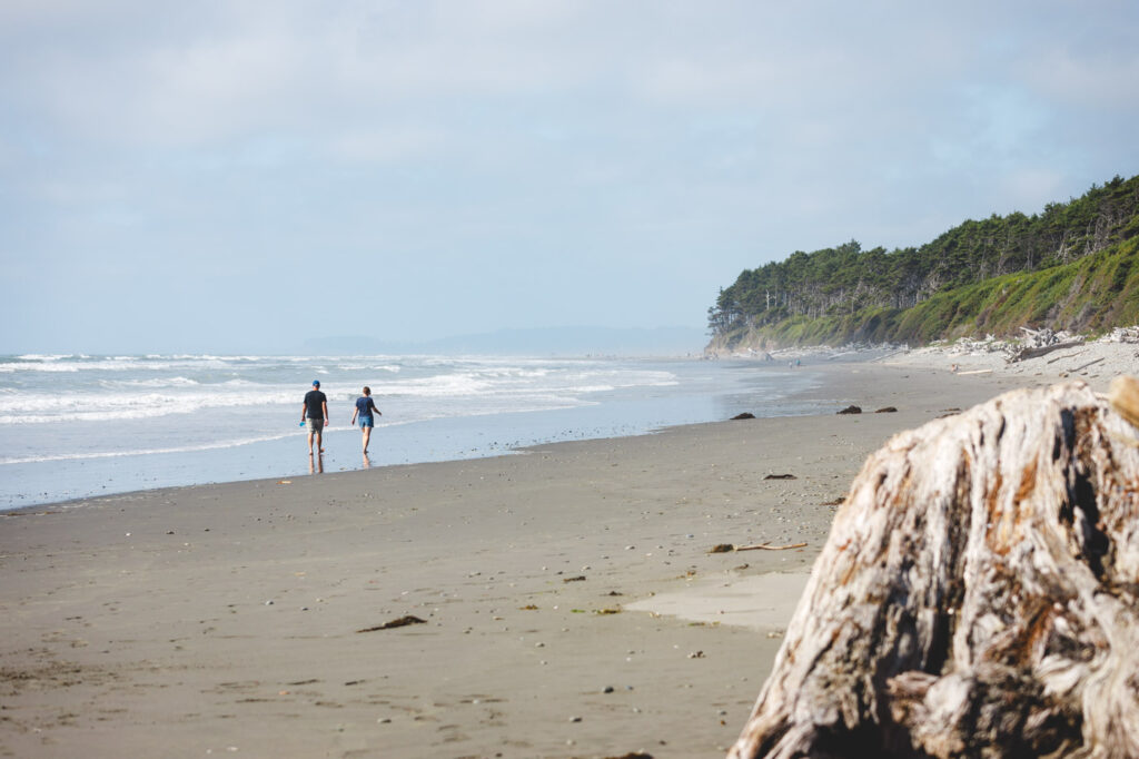 Two tourists walking along a fairly empty Kalaloch Beach 2 on a clear day.