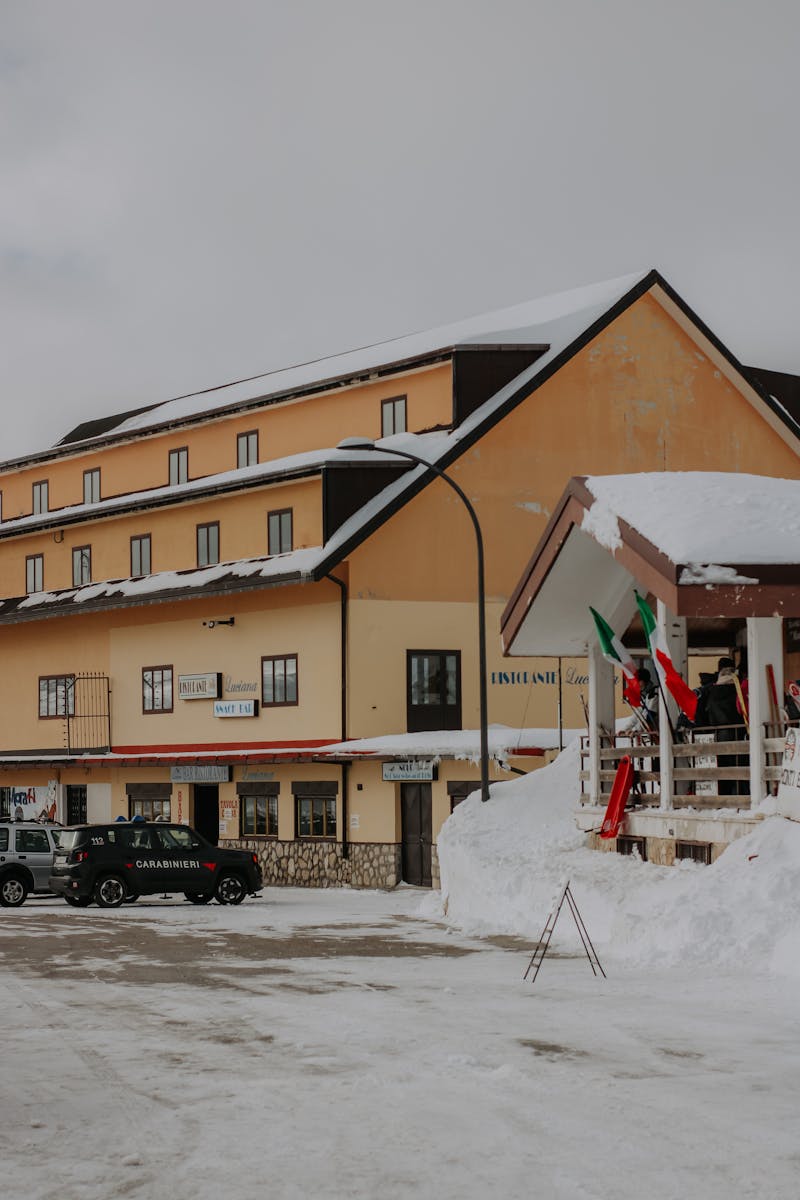 Snow-covered street with a building and car in a winter town.
