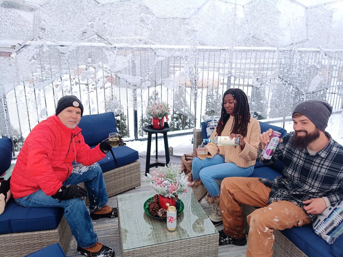 Three people relaxing in an igloo-style glamping space